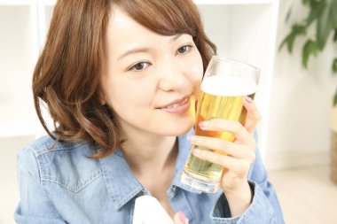 Neşeli Japon kadın evde bira içiyor.