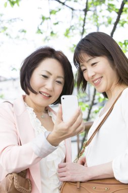 Akıllı telefonlu iki Asyalı kadın selfie çekiyor.