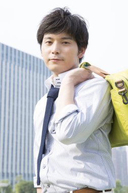 Çantalı genç bir adam şehirde duruyor.