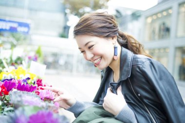 Renkli çiçeklere bakarken gülümseyen bir kadın.