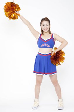 Güzel Japon ponpon kız stüdyoda dans ediyor. Pom ponponları kaldıran güzel genç bir kadının yakın plan portresi.