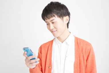 Stüdyo fotoğrafı, akıllı telefon kullanan sıradan giysili genç adam.