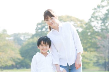 Genç Asyalı anne ve küçük oğlu parkta oynuyorlar.