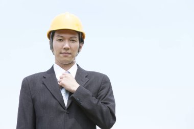 Takım elbiseli ve kasklı Asyalı iş adamının portresi.