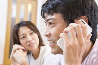 Çift evde cep telefonuyla konuşuyor. 