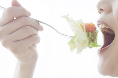 Çatalla taze salata yiyen kişi.