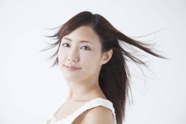 Temiz tenli güzel, genç bir Asyalı kadın kameraya bakıyor. 