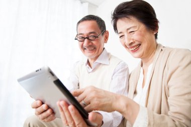 Evde dijital tablet kullanan yaşlı çift 