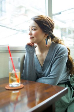 Güzel Asyalı kadın kafede soğuk içecek içiyor.
