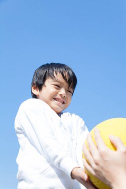 Parkta top oynayan yakışıklı Asyalı çocuk.