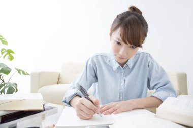 Genç Japon kadın evde kitap ve kalemle okuyor. 