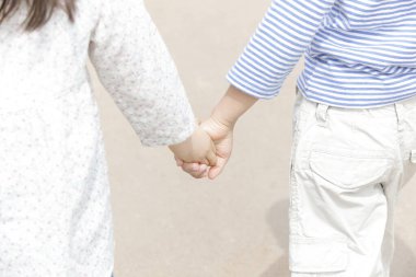 Dışarıda el ele tutuşan iki çocuk.