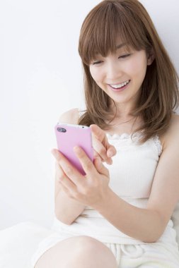 Evde cep telefonu kullanan genç bir kadın. 