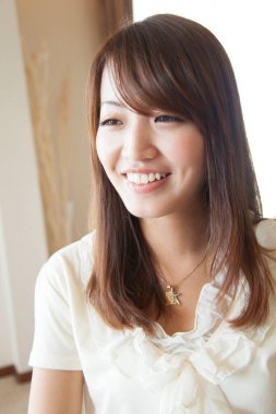 Kapalı alanda gülümseyen genç Asyalı kadın. 