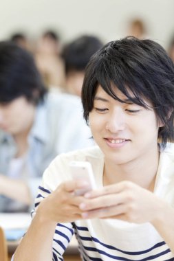 Sınıfta akıllı telefon kullanan genç adam.