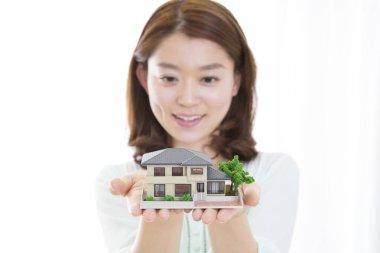 Asyalı bir kadın ev modelini tutuyor.