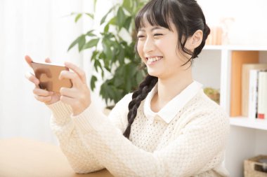 Güzel Asyalı genç kadın akıllı telefon kullanıyor.