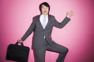 Pembe arka planda korkmuş genç Asyalı iş adamı