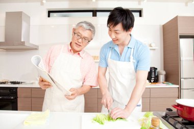 Mutlu baba ve oğul ev mutfağında birlikte yemek pişiriyor.