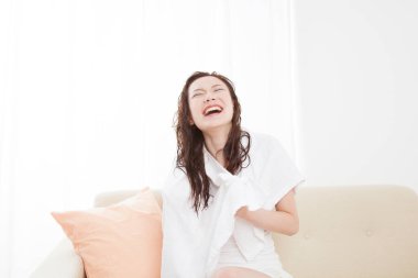 Sırıtkan Asyalı genç kadın, ıslak saçlar ve duştan sonra beyaz havlu.