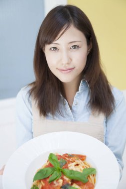 Evde makarna pişiren Asyalı kadın.