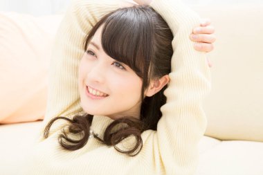 Genç Asyalı kadın kanepede dinleniyor.