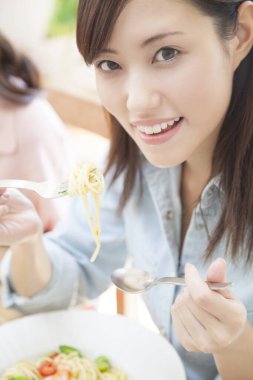 Genç Asyalı kadın spagetti yiyor.