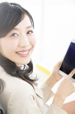 Ofiste tablet bilgisayar kullanan Asyalı iş kadını 