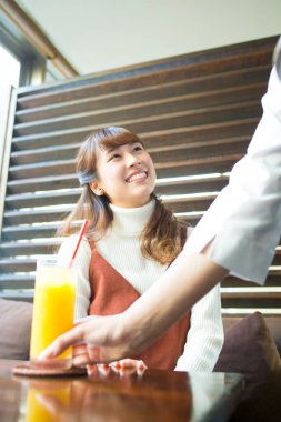 Garson kafede Asyalı kadına portakal suyu servisi yapıyor.