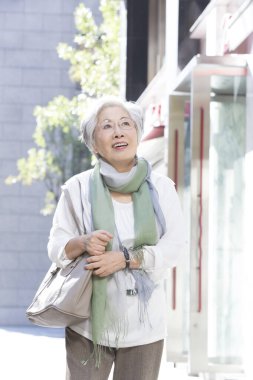 Kaldırımda elinde çantasıyla yürüyen bir kadın.