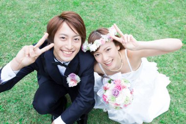 Genç Asyalı düğün çifti parkta poz veriyor.