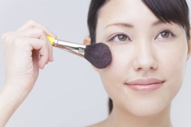 Genç Asyalı kadın makyaj yapıyor.