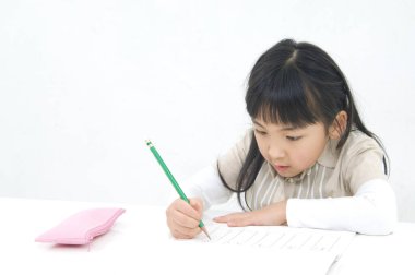 Not defterine yazı yazan Asyalı küçük kız.