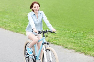 Parkta bisiklete binen mutlu kadın