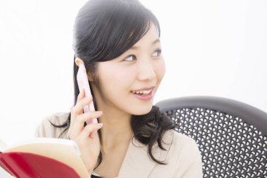 Ofiste akıllı telefondan konuşan not defterli genç bir kadın.