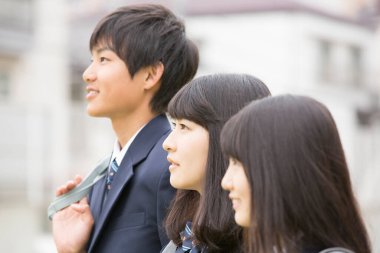 Okulda dışarıda dikilen bir grup öğrenci üniforma giyiyor. 