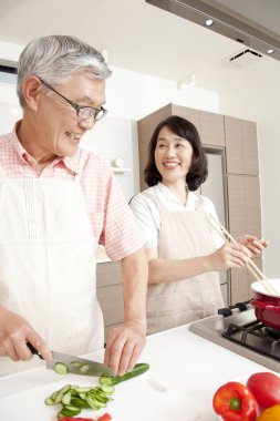 Gülümseyen çift modern mutfakta birlikte yemek pişiriyor.