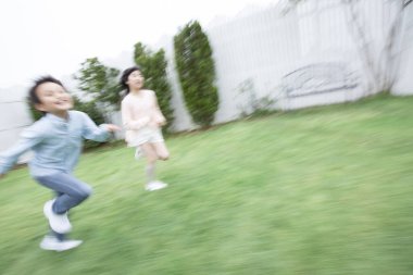 Mutlu Asyalı kız ve erkek açık havada koşuyorlar.