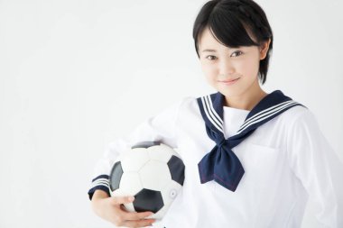 Okul üniformalı, futbol topuyla gülümseyen Asyalı kızın portresi.
