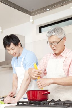 Mutlu baba ve oğul ev mutfağında birlikte yemek pişiriyor.