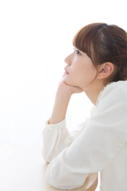 Asyalı kadın elleri çenesinde düşünüyor.