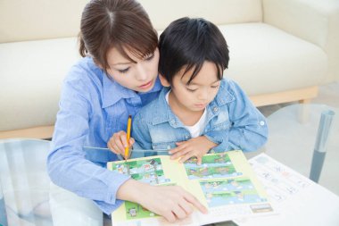 Genç Japon kadın oğluyla ev ödevi yapıyor.