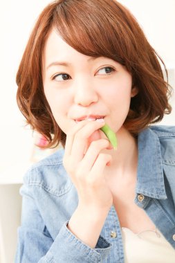 Yeşil bezelye yiyen ve televizyon izleyen güzel Japon kadının portresi. 