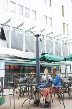 İki Asyalı bayan arkadaş sokak kafesinde oturuyor.