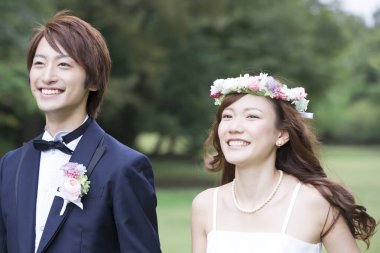 Genç Asyalı düğün çifti parkta poz veriyor.