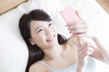 Yatakta cep telefonu kullanan güzel bir kız.