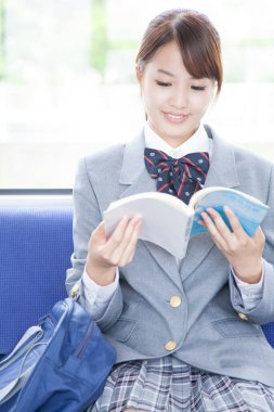 Okul üniformalı tatlı Japon kız metroda giderken kitap okuyor. 