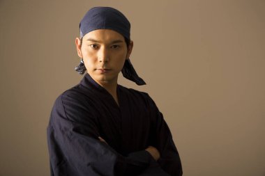 Asyalı genç adam geleneksel kıyafetler giyiyor ve stüdyoda poz veriyor.