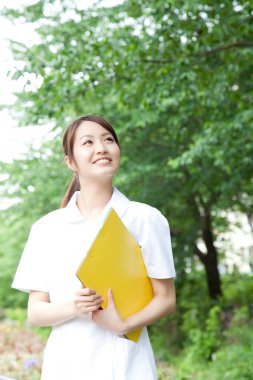 Dosyası açık havada olan Asyalı genç bir kız öğrenci.