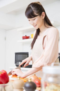 Genç bir kadın mutfakta yemek pişiriyor.